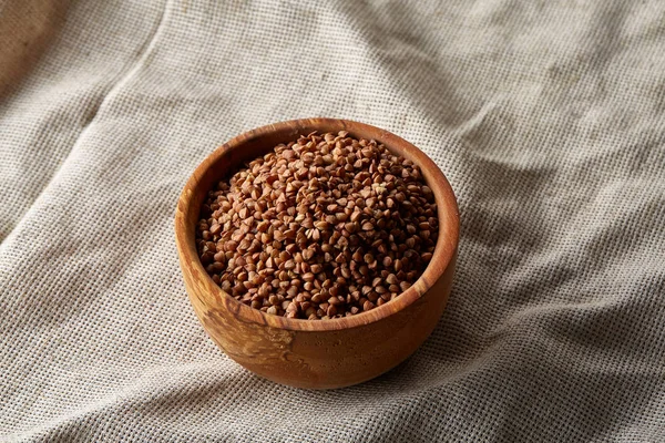 Bowl full of buckwheat grains on rustic wooden table, close-up, selective focus, shallow depth of field. — Stock Photo, Image