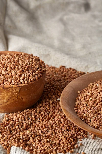 Bowl full of buckwheat grains on rustic wooden table, close-up, selective focus, shallow depth of field.