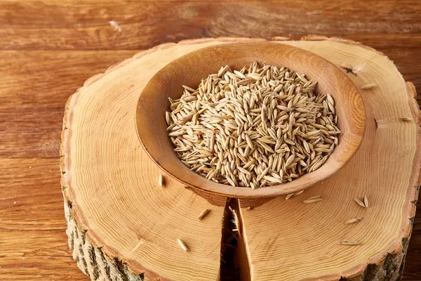 Ahşap arka plan, üstten görünüm, yakın çekim, makro, sığ derinlik-in tarla soyulmamış yulaf taneleri yığını.