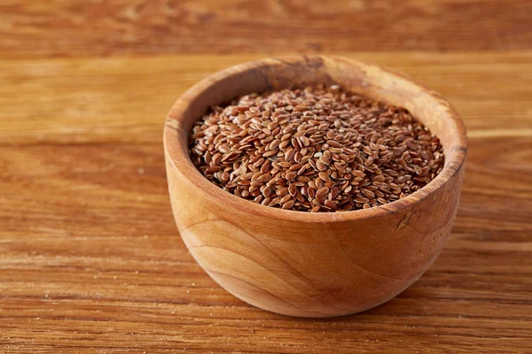 Bowl full of buckwheat grains on rustic wooden table, close-up, selective focus, shallow depth of field.