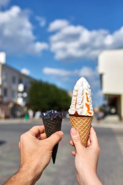 Bir dondurma sığ derinlik-in tarla onun elinde olan yol boyunca yürüyüş kadın bir ilk kişi görünümü.