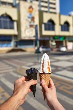 Bir dondurma sığ derinlik-in tarla onun elinde olan yol boyunca yürüyüş kadın bir ilk kişi görünümü.