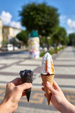 Bir dondurma sığ derinlik-in tarla onun elinde olan yol boyunca yürüyüş kadın bir ilk kişi görünümü.