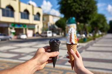 Bir dondurma sığ derinlik-in tarla onun elinde olan yol boyunca yürüyüş kadın bir ilk kişi görünümü.
