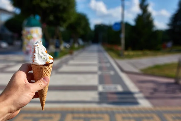 Een eerste persoon bekijken, een persoon lopen langs de weg met een ijsje in zijn handen, ondiepe scherptediepte. — Stockfoto