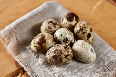 Bir günlük bir peçeteye yuvarlağına düzenlenmiş ahşap arka plan, yakın çekim, seçici odak bıldırcın yumurtası.