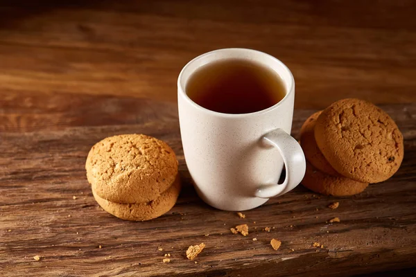 Taza de porcelana blanca de té y galletas dulces en pieza de madera sobre fondo de madera, vista superior, enfoque selectivo — Foto de Stock