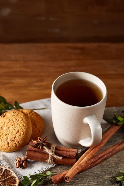 Concepto tradicional de té de Navidad con una taza de té caliente, galletas y decoraciones en una mesa de madera, enfoque selectivo —  Fotos de Stock