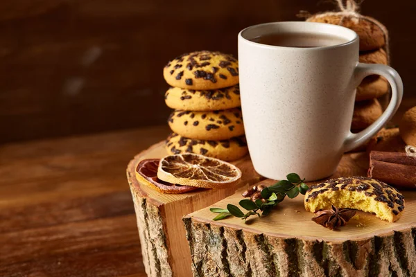 Weihnachtskonzept mit einer Tasse heißem Tee, Plätzchen und Dekorationen auf einem Baumstamm über Holzgrund, selektiver Fokus — Stockfoto