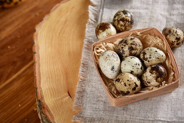 Sammansättningen av ägg vaktlar box, ägg på en hemvävd servett på en logg över trä bakgrund, ovanifrån — Stockfoto