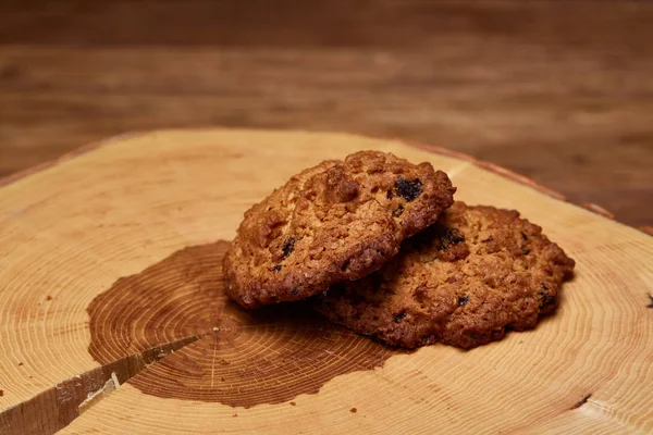 Bande de biscuits au chocolat sur une bûche ronde en bois sur fond bois rustique, gros plan, mise au point sélective . — Photo