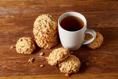 Beyaz porselen kupa çay ve tatlı kurabiye ahşap arka plan, üstten görünüm, seçici odak