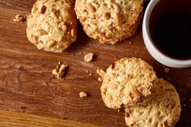 Beyaz porselen kupa çay ve tatlı kurabiye ahşap arka plan, üstten görünüm, seçici odak