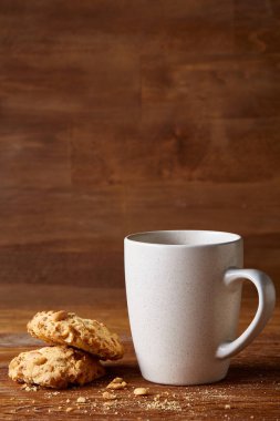 Beyaz porselen kupa çay ve tatlı kurabiye ahşap arka plan, üstten görünüm, seçici odak