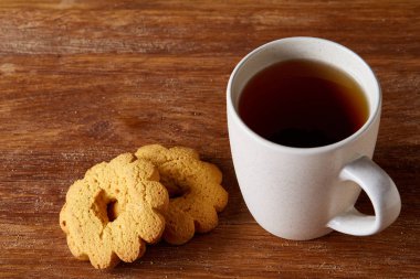 Beyaz porselen kupa çay ve tatlı kurabiye ahşap arka plan, üstten görünüm, seçici odak