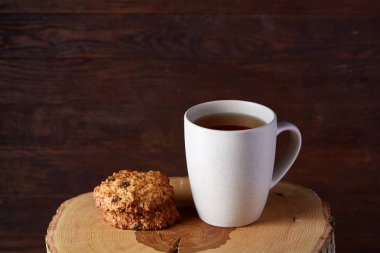 Beyaz porselen kupa çay ve tatlı kurabiye ahşap arka plan, üstten görünüm, seçici odak