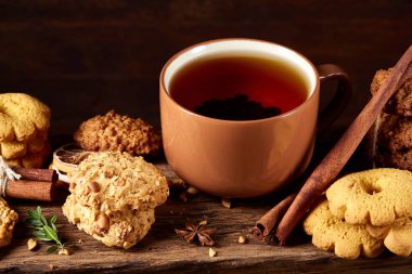 Kavramsal şenlikli bileşimi ile bir fincan sıcak çay, kurabiye ve spicies bir ahşap varil, seçici odak, yakın çekim