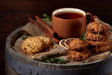 Kavramsal şenlikli bileşimi ile bir fincan sıcak çay, kurabiye ve spicies bir ahşap varil, seçici odak, yakın çekim