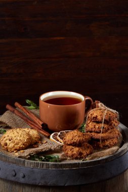 Kavramsal şenlikli bileşimi ile bir fincan sıcak çay, kurabiye ve spicies bir ahşap varil, seçici odak, yakın çekim