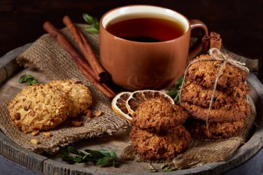 Kavramsal şenlikli bileşimi ile bir fincan sıcak çay, kurabiye ve spicies bir ahşap varil, seçici odak, yakın çekim