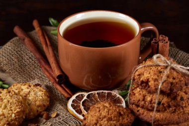 Kavramsal şenlikli bileşimi ile bir fincan sıcak çay, kurabiye ve spicies bir ahşap varil, seçici odak, yakın çekim