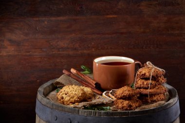 Kavramsal şenlikli bileşimi ile bir fincan sıcak çay, kurabiye ve spicies bir ahşap varil, seçici odak, yakın çekim