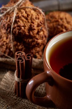 Kavramsal şenlikli bileşimi ile bir fincan sıcak çay, kurabiye ve spicies bir ahşap varil, seçici odak, yakın çekim