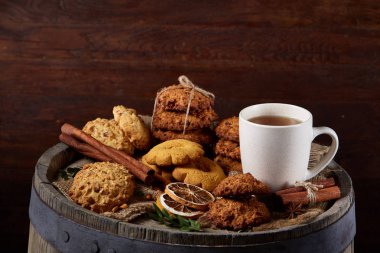 Kavramsal şenlikli bileşimi ile bir fincan sıcak çay, kurabiye ve spicies bir ahşap varil, seçici odak, yakın çekim