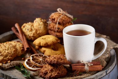 Kavramsal şenlikli bileşimi ile bir fincan sıcak çay, kurabiye ve spicies bir ahşap varil, seçici odak, yakın çekim