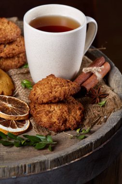 Kavramsal şenlikli bileşimi ile bir fincan sıcak çay, kurabiye ve spicies bir ahşap varil, seçici odak, yakın çekim