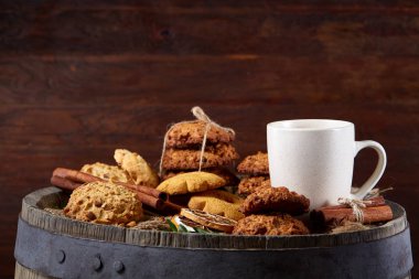 Kavramsal şenlikli bileşimi ile bir fincan sıcak çay, kurabiye ve spicies bir ahşap varil, seçici odak, yakın çekim