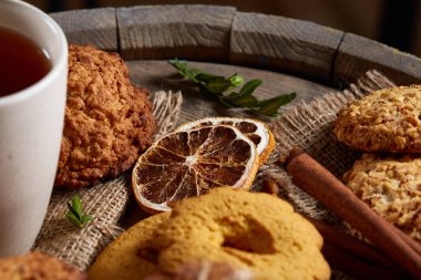 Kavramsal şenlikli bileşimi ile bir fincan sıcak çay, kurabiye ve spicies bir ahşap varil, seçici odak, yakın çekim