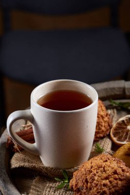Kavramsal şenlikli bileşimi ile bir fincan sıcak çay, kurabiye ve spicies bir ahşap varil, seçici odak, yakın çekim