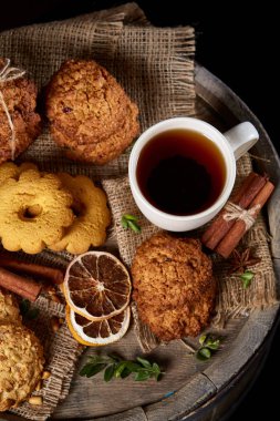 Kavramsal şenlikli bileşimi ile bir fincan sıcak çay, kurabiye ve spicies bir ahşap varil, seçici odak, yakın çekim
