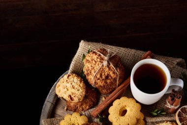 Beyaz porselen kupa çay ve tatlı kurabiye ahşap arka plan, üstten görünüm, seçici odak
