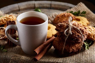 Beyaz porselen kupa çay ve tatlı kurabiye ahşap arka plan, üstten görünüm, seçici odak