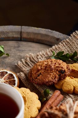 Beyaz porselen kupa çay ve tatlı kurabiye ahşap arka plan, üstten görünüm, seçici odak