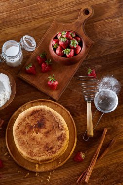 Top çilekli pasta ya da kek üzerine ahşap masa, düz yatıyordu yemek pişirmek için ham maddeler görüntüleyin. Fırın arka plan.