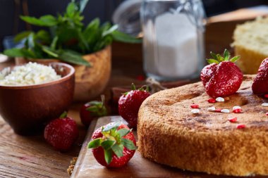 Top çilekli pasta ya da kek üzerine ahşap masa, düz yatıyordu yemek pişirmek için ham maddeler görüntüleyin. Fırın arka plan.