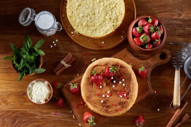 Top çilekli pasta ya da kek üzerine ahşap masa, düz yatıyordu yemek pişirmek için ham maddeler görüntüleyin. Fırın arka plan.