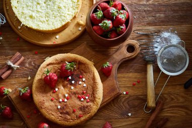Top çilekli pasta ya da kek üzerine ahşap masa, düz yatıyordu yemek pişirmek için ham maddeler görüntüleyin. Fırın arka plan.