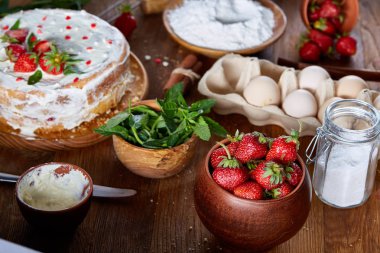 Top çilekli pasta ya da kek üzerine ahşap masa, düz yatıyordu yemek pişirmek için ham maddeler görüntüleyin. Fırın arka plan.