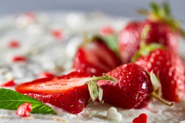Çilek ve beyaz dokulu arka planda, seçici odak nane yaprakları ile süslenmiş krem şanti ile tart