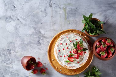 Çilek ve beyaz dokulu arka planda, seçici odak nane yaprakları ile süslenmiş krem şanti ile tart