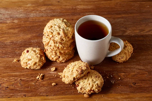 Beyaz porselen kupa çay ve tatlı kurabiye ahşap arka plan, üstten görünüm, seçici odak