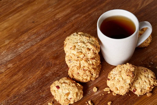 White porcelain mug of tea and sweet cookies on wooden background, top view, selective focus — Stock Photo, Image