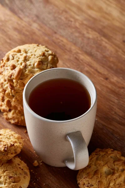 Beyaz porselen kupa çay ve tatlı kurabiye ahşap arka plan, üstten görünüm, seçici odak