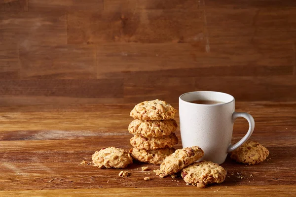 Taza de porcelana blanca de té y galletas dulces sobre fondo de madera, vista superior, enfoque selectivo — Foto de Stock