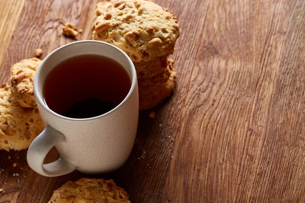 Caneca de porcelana branca de chá e biscoitos doces no fundo de madeira, vista superior, foco seletivo — Fotografia de Stock