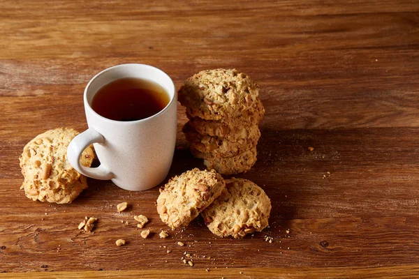 Beyaz porselen kupa çay ve tatlı kurabiye ahşap arka plan, üstten görünüm, seçici odak